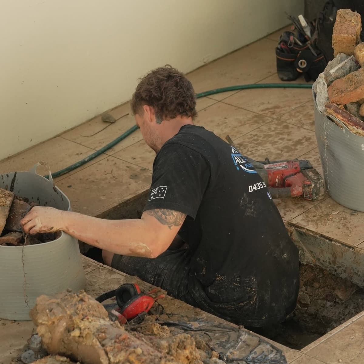 Josh digging out a broken drain under a patio